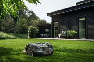 Robotic lawn mower operating on a well-maintained lawn in a modern garden setting.