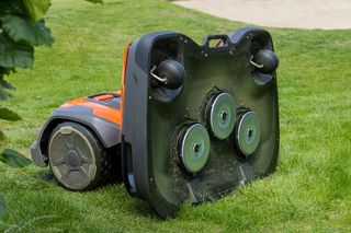 Mähroboter auf dem Kopf stehend auf Gras gedreht, zeigt seine Schneidmesser.