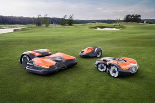 Three robotic lawn mowers on a golf course lawn.