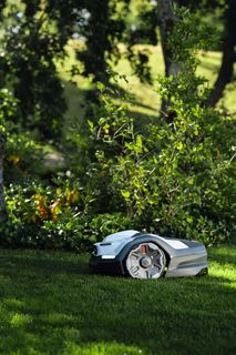 Mähroboter auf gepflegtem Rasen in einer Gartenumgebung.