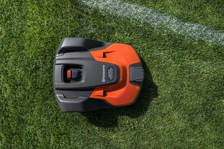Robotic lawn mower on a grass field, viewed from above.