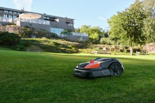 Robotic lawn mower operating on a well-maintained lawn in front of a hotel.