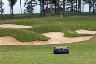 Robotic lawn mower operating on a golf course near sand bunkers.