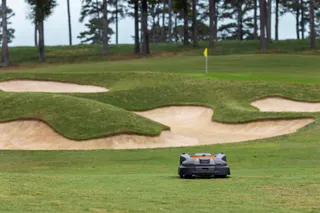 Robotic lawn mower operating on a golf course near sand bunkers.