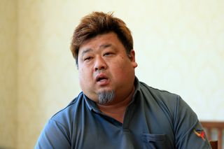 明るい模様の壁に向かって屋内で話している人物のクローズアップポートレート。