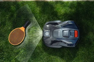 Robotic lawn mower operating on a grass lawn, viewed from above.