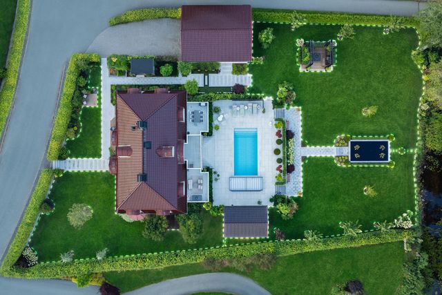 Aerial view of a landscaped garden with a swimming pool, patio, and pond.