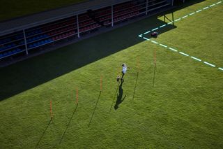 A person practicing soccer drills on a grassy field with training cones.
