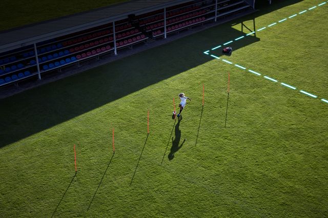 Eine Person, die Fußballübungen auf einem Rasenplatz mit Trainingshütchen übt.