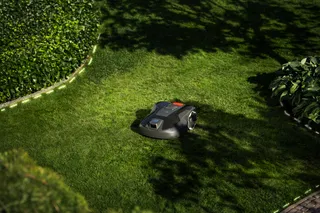 Robotic lawn mower operating in a well-maintained garden.