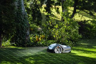 Robotic lawn mower operating on a grassy lawn with a grid overlay.
