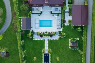 Aerial view of a large house with a well-maintained garden and a small pond.