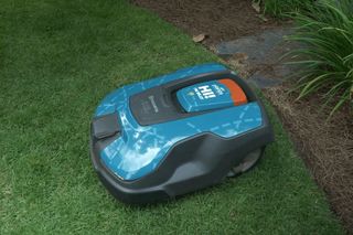 Robotic lawn mower operating in a garden with a satellite signal icon overlay.