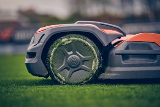 Nahaufnahme eines mit Grasschnitt bedeckten Mähroboters auf einem Rasen.