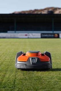 Robot tagliaerba al lavoro su un campo sportivo ben curato.