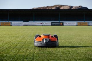 Robotic lawn mower operating on a well-maintained sports field.