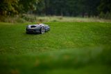 Robotic lawn mower operating on a grassy slope in a garden.