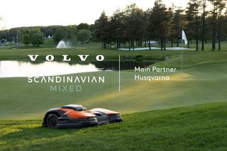 Two robotic lawn mowers on a golf course with Volvo Scandinavian Mixed event branding.