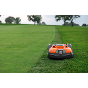 Tondeuse à gazon robotisée fonctionnant sur un bord de gazon soigneusement taillé dans un jardin.