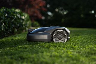 Robotic lawn mower operating on a grassy lawn with blurred background.