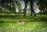 Robotic lawn mower operating in a garden with a satellite signal icon overlay.