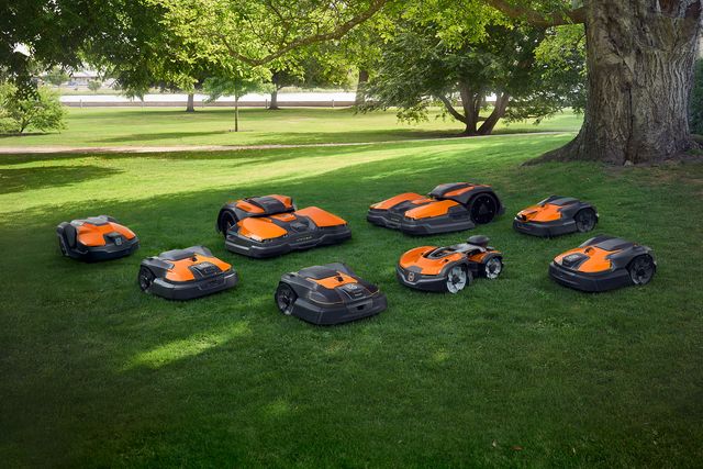 Multiple robotic lawn mowers in a park setting.