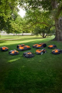 Multiple robotic lawn mowers in a park setting.