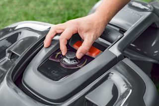 Une personne qui règle les réglages d’un robot tondeuse.