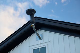 Satellite dish mounted on the side of a house roof.