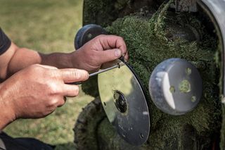 Uma pessoa a ajustar a lâmina de um cortador de relva para o exterior.
