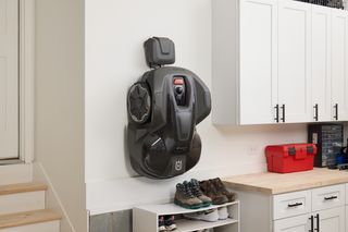 Husqvarna robotic lawn mower mounted on a wall in a garage setting.