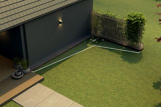 A garden with a wooden fence and neatly trimmed grass, adjacent to a modern house.