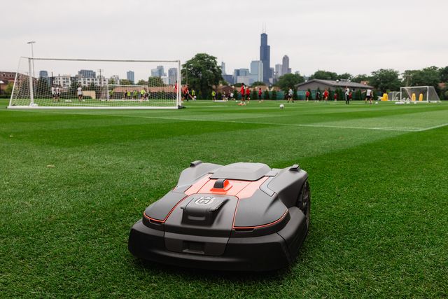 Husqvarna robotic lawn mower on a soccer field during team practice.