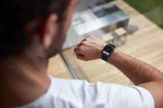 A person wearing a smartwatch, checking notifications while standing indoors.