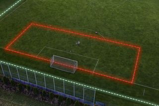 Un terrain de football avec une superposition de limite rouge et un poteau de but, vu d’en haut.