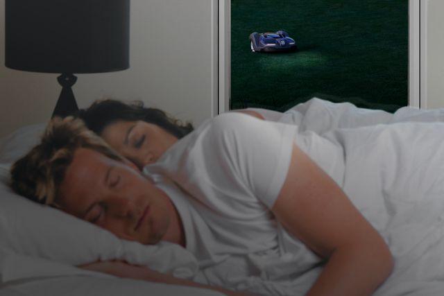 A robotic lawn mower operating outside a window while a person sleeps indoors.