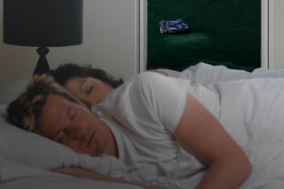 Robotická kosačka pracujúca za oknom, zatiaľ čo človek spí vo vnútri.