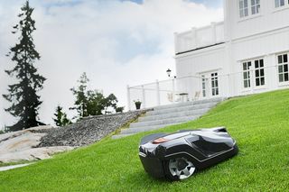 Mähroboter auf einer Wiese neben einem weißen Haus.