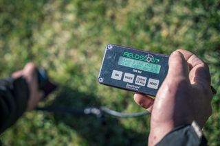 Ένα άτομο που κατέχει μια ψηφιακή συσκευή μέτρησης πεδίου που εμφανίζει δεδομένα.