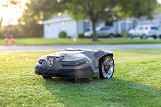 Robotic lawn mower operating on a grassy lawn in a residential area.