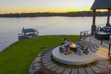 A group of people enjoying a sunset dinner on a deck overlooking a serene lake.