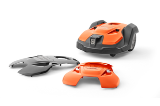 Kosiarka automatyczna Husqvarna z dwiema wymiennymi osłonami wyświetlanymi w warunkach studyjnych.