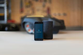 Смартфон із додатком Amazon Alexa поруч із розумною колонкою в домашніх умовах.