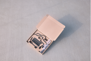 Open cardboard box containing various tools and accessories, displayed on a concrete surface.