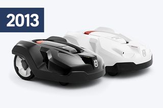 Дві роботизовані газонокосарки Husqvarna 2013 року, одна чорна та одна біла, розташовані поруч.