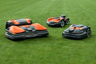 Drie robotmaaiers op een grasveld.