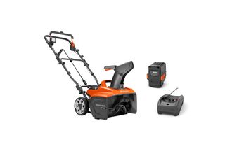 Front view of a Husqvarna single-stage snow blower with battery and charger.