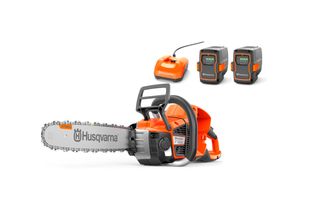 Sett fra siden av en Husqvarna-motorsag med to batterier og en lader i studiosammenheng.