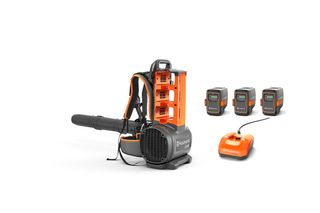 Sett forfra av en ryggbåren løvblåser fra Husqvarna med tre batterier og en lader.