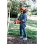 Un enfant tenant une tronçonneuse Husqvarna dans un jardin, portant une tenue de travail.